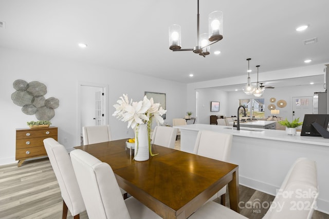 dining space with light wood-type flooring, sink, and a chandelier