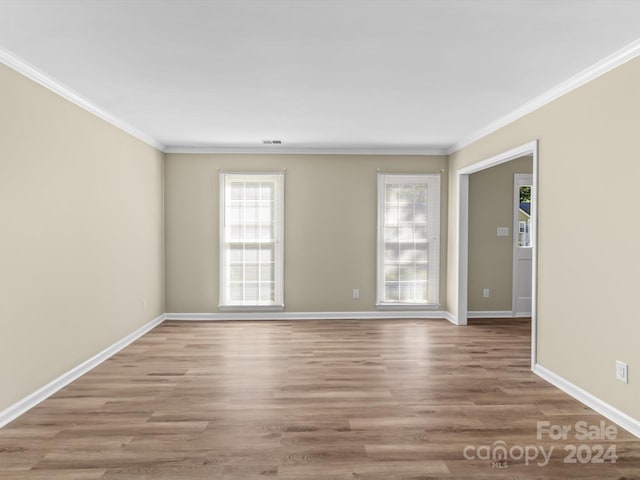 spare room with ornamental molding and light wood-type flooring