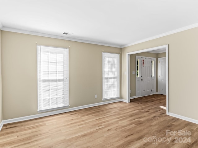 empty room with crown molding and light hardwood / wood-style flooring