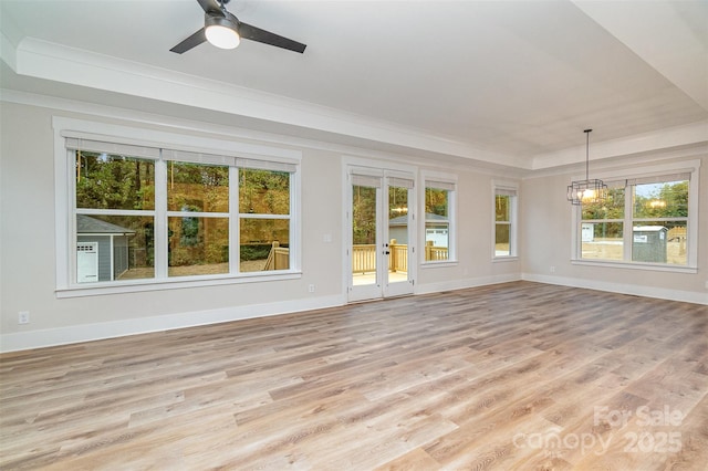 unfurnished sunroom with french doors, ceiling fan with notable chandelier, and a tray ceiling