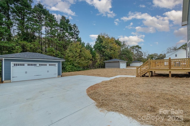 view of yard featuring a garage, a deck, and an outdoor structure