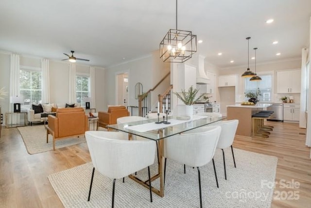 dining space featuring ceiling fan with notable chandelier, light hardwood / wood-style flooring, and crown molding