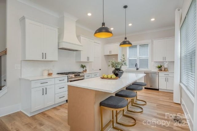 kitchen with white cabinetry, custom exhaust hood, a breakfast bar area, appliances with stainless steel finishes, and a center island