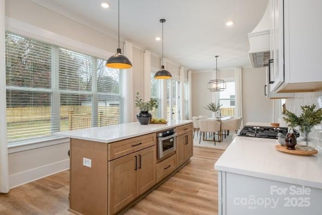 kitchen with appliances with stainless steel finishes, a kitchen island, white cabinetry, and hanging light fixtures