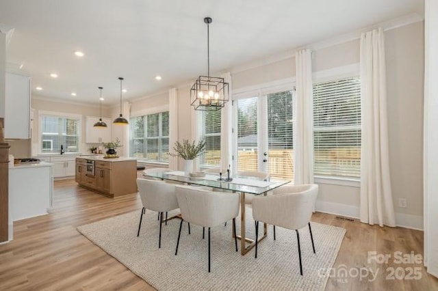 dining space with a healthy amount of sunlight, ornamental molding, and light hardwood / wood-style flooring