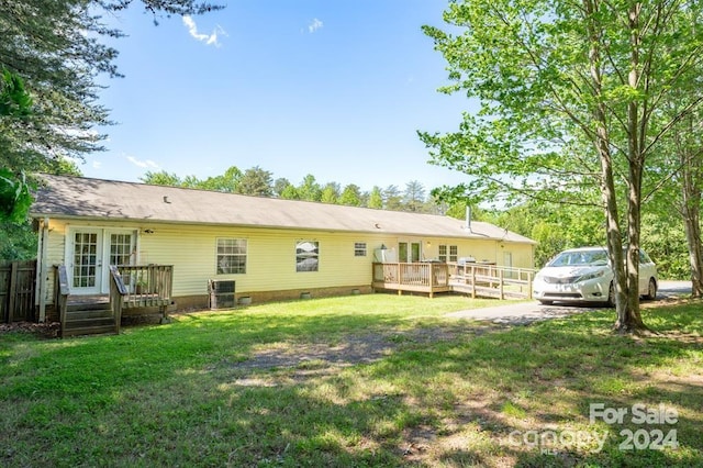 rear view of property featuring central AC, a yard, and a wooden deck