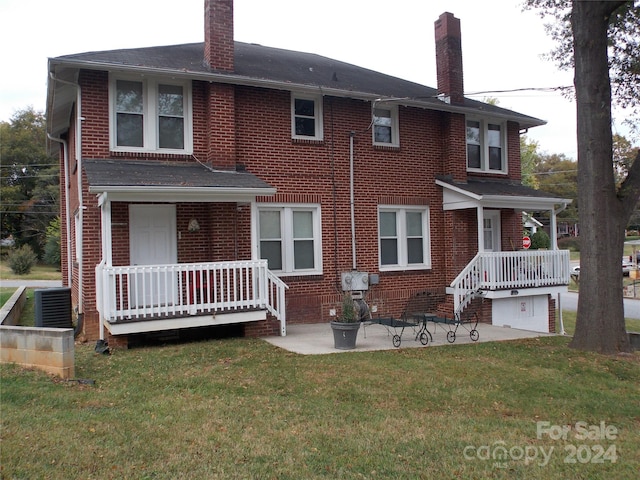 rear view of property featuring covered porch, cooling unit, and a lawn