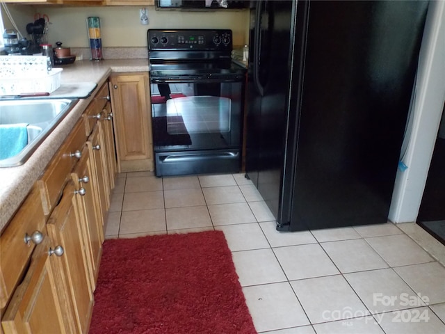 kitchen featuring black appliances, light tile patterned floors, and sink