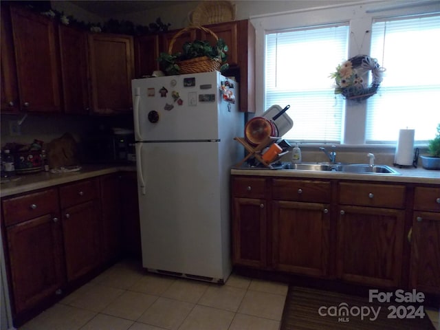 kitchen featuring light tile patterned flooring, sink, and white fridge