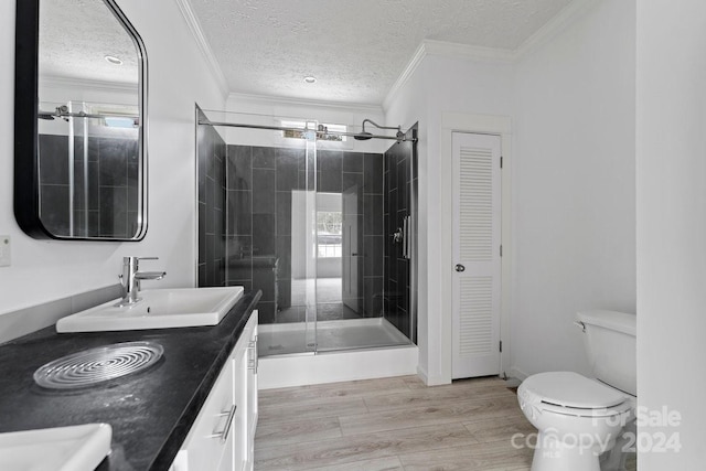 bathroom with toilet, a shower with shower door, wood-type flooring, crown molding, and vanity