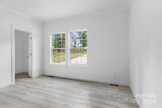 unfurnished room with ornamental molding, light hardwood / wood-style flooring, and a textured ceiling