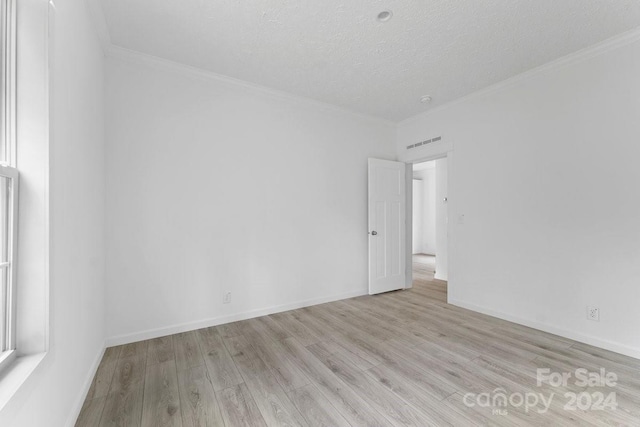 spare room featuring crown molding, a textured ceiling, and light wood-type flooring