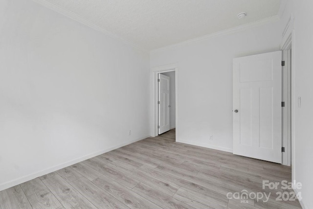 empty room with light hardwood / wood-style floors, a textured ceiling, and ornamental molding