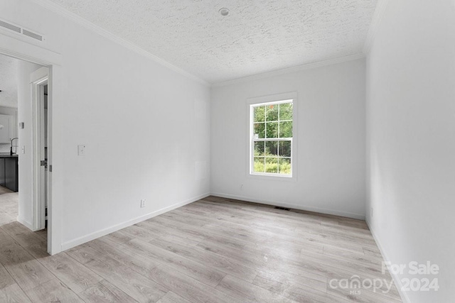 spare room with crown molding, a textured ceiling, and light hardwood / wood-style flooring