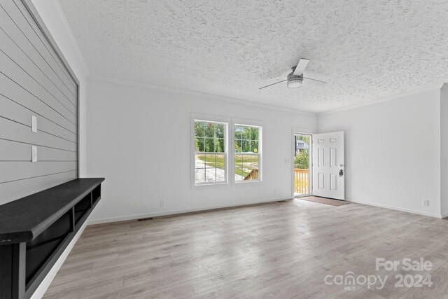 unfurnished living room with light hardwood / wood-style floors, crown molding, a textured ceiling, and ceiling fan