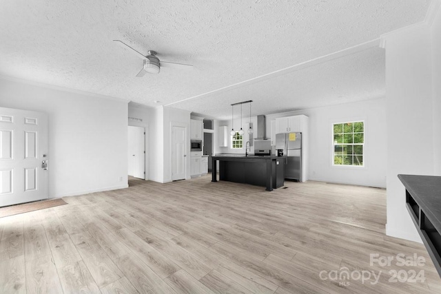 unfurnished living room featuring light hardwood / wood-style floors, a textured ceiling, sink, and ceiling fan