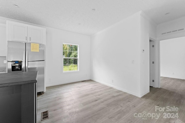 unfurnished living room featuring light hardwood / wood-style flooring and a textured ceiling