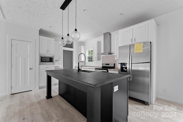 kitchen featuring wall chimney range hood, sink, stainless steel appliances, white cabinets, and a center island with sink