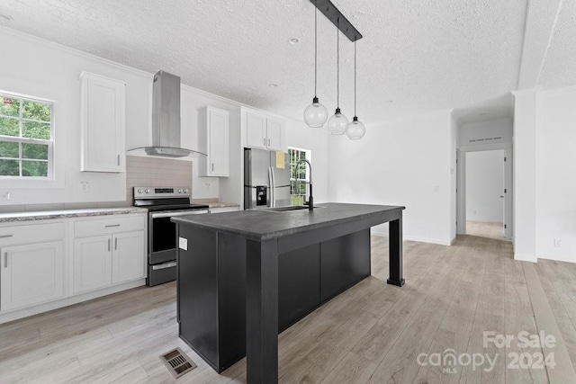 kitchen with wall chimney exhaust hood, stainless steel appliances, a healthy amount of sunlight, a center island with sink, and white cabinetry