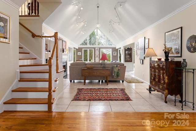 interior space featuring ornamental molding, track lighting, light tile patterned flooring, and high vaulted ceiling