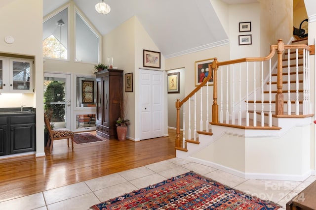 foyer entrance with ornamental molding, sink, light hardwood / wood-style flooring, and high vaulted ceiling