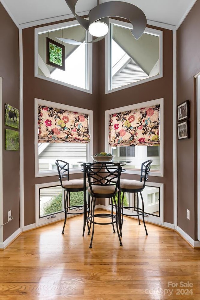 dining area featuring a towering ceiling, light hardwood / wood-style flooring, and a healthy amount of sunlight