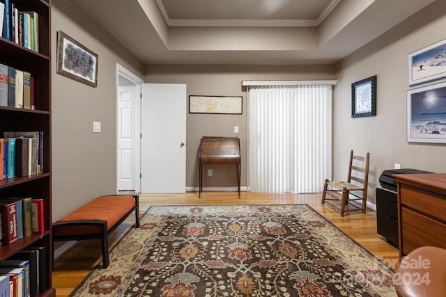 living area featuring crown molding, a tray ceiling, and light hardwood / wood-style flooring