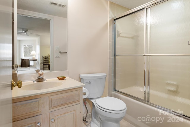 full bathroom featuring toilet, vanity, combined bath / shower with glass door, a textured ceiling, and ceiling fan