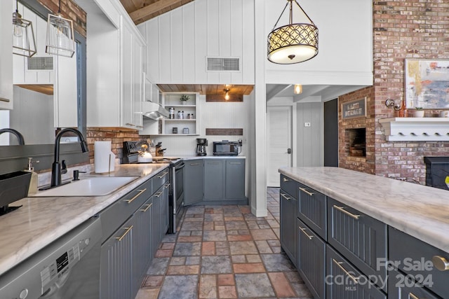 kitchen with beam ceiling, hanging light fixtures, brick wall, sink, and appliances with stainless steel finishes