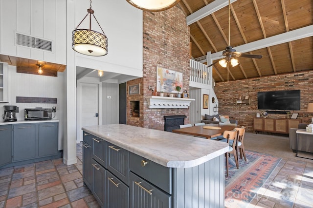 kitchen with high vaulted ceiling, wooden ceiling, a brick fireplace, beamed ceiling, and a center island