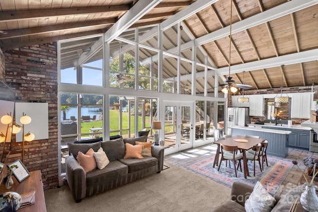 living room featuring a healthy amount of sunlight, beamed ceiling, a water view, and ceiling fan