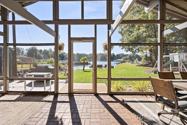 sunroom / solarium with a water view, vaulted ceiling, and plenty of natural light