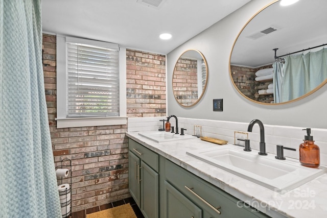 bathroom featuring vanity and brick wall