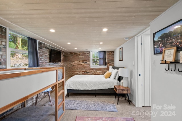 carpeted bedroom with wood ceiling and brick wall