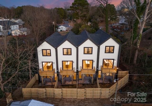 back house at dusk featuring a balcony