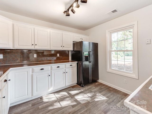 kitchen with white cabinetry, tasteful backsplash, light hardwood / wood-style floors, and black fridge