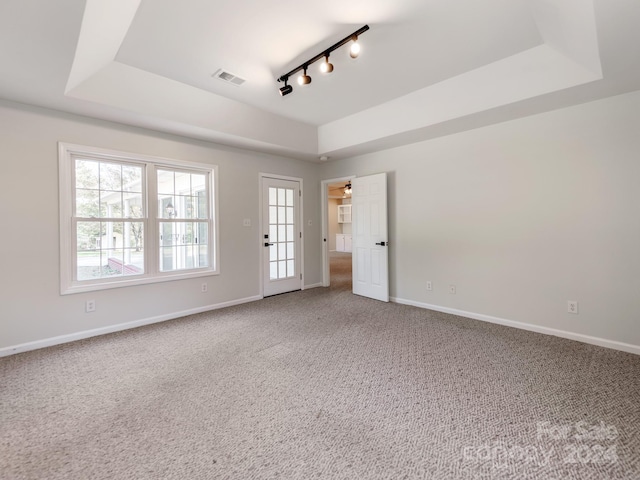 spare room featuring carpet, track lighting, a tray ceiling, and ceiling fan