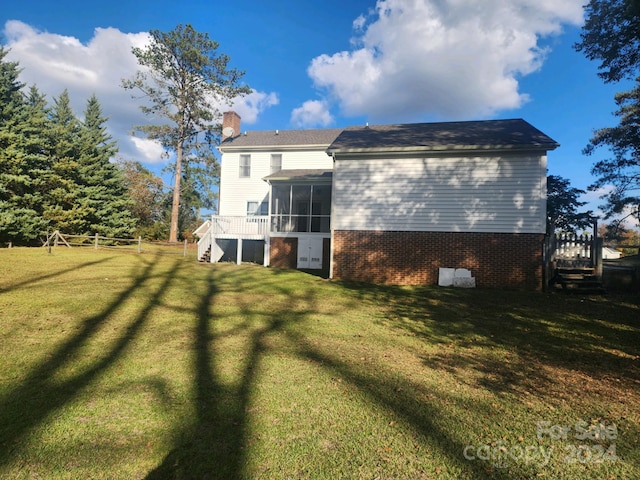 rear view of property featuring a yard and a sunroom