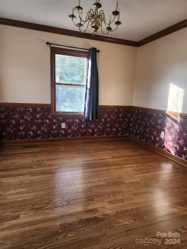 spare room with a chandelier, crown molding, and wood-type flooring