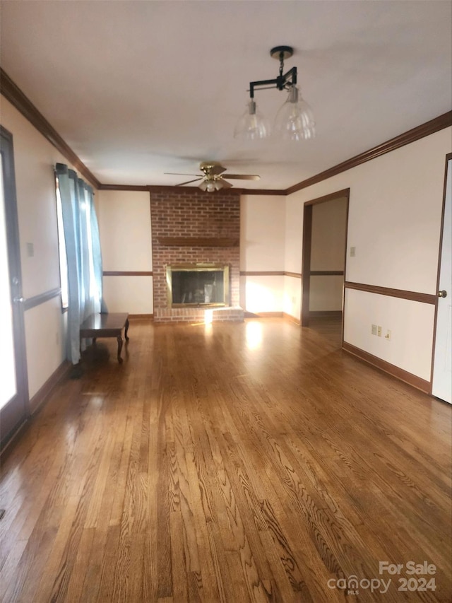 unfurnished living room featuring ornamental molding, hardwood / wood-style floors, ceiling fan, and a brick fireplace