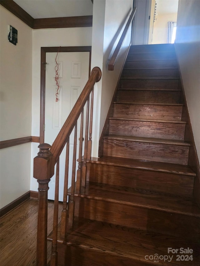 staircase featuring wood-type flooring and ornamental molding