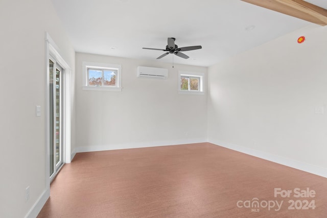 carpeted spare room featuring beamed ceiling, a wall unit AC, ceiling fan, and plenty of natural light