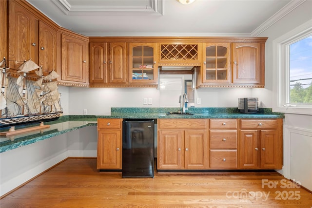 kitchen with dark stone countertops, sink, crown molding, and light hardwood / wood-style floors