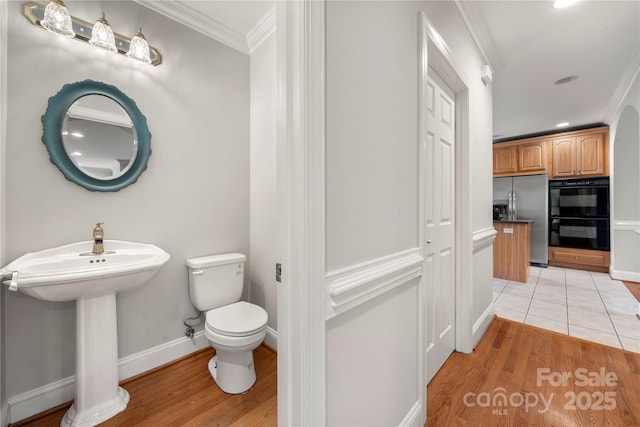 bathroom featuring sink, crown molding, wood-type flooring, and toilet