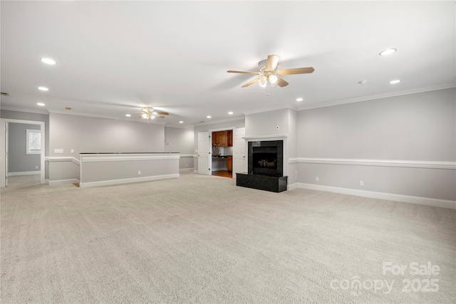 unfurnished living room with ceiling fan, ornamental molding, a premium fireplace, and light colored carpet