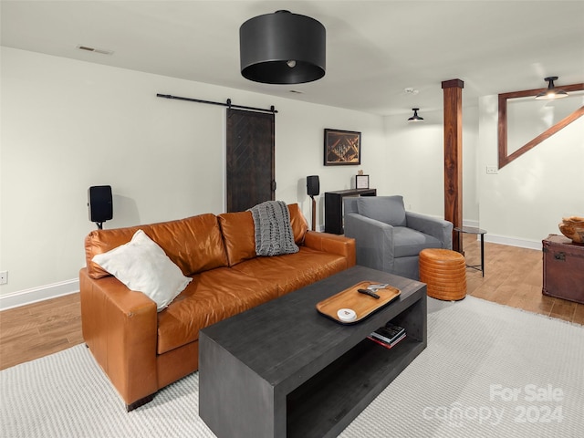 living room with a barn door and light wood-type flooring