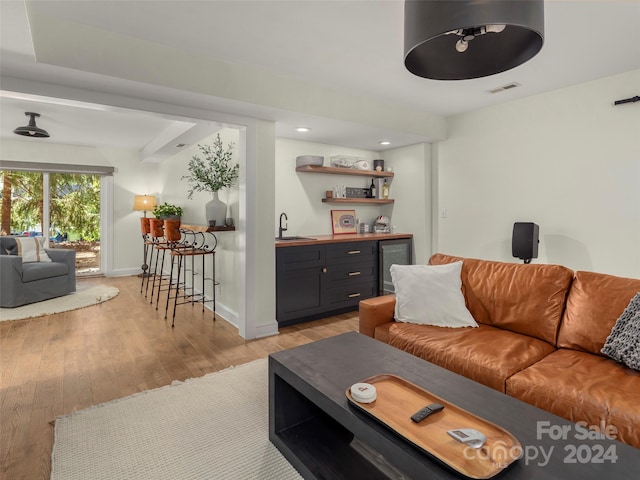 living room with wine cooler, sink, and light wood-type flooring