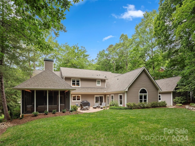 rear view of house featuring a sunroom and a lawn