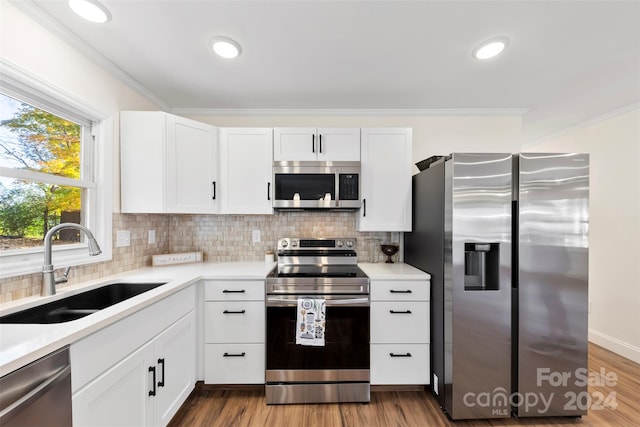 kitchen with white cabinets, tasteful backsplash, hardwood / wood-style floors, appliances with stainless steel finishes, and sink