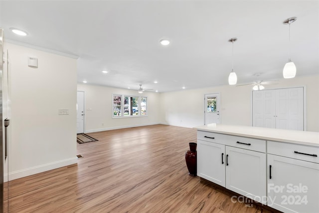 kitchen with white cabinets, decorative light fixtures, light wood-type flooring, and ceiling fan